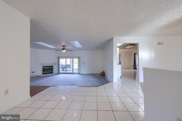 unfurnished living room featuring a ceiling fan, a skylight, a glass covered fireplace, and a textured ceiling
