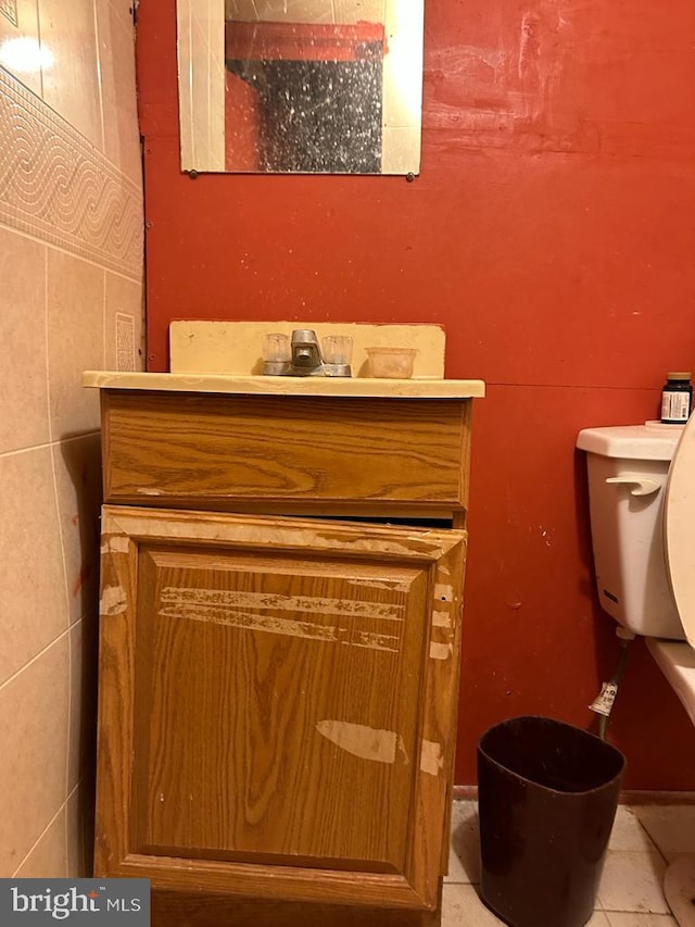 bathroom featuring vanity, toilet, tile patterned floors, and tile walls