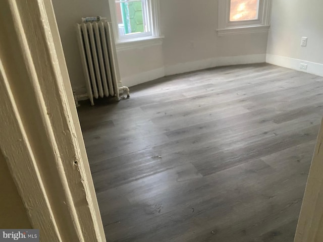 unfurnished room featuring radiator and dark hardwood / wood-style floors