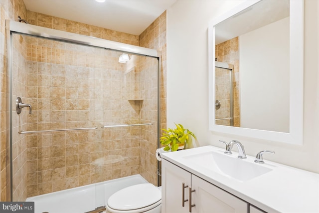 bathroom featuring vanity, a shower with shower door, and toilet