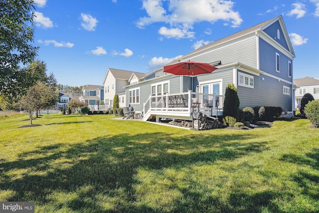 rear view of property featuring a wooden deck and a lawn