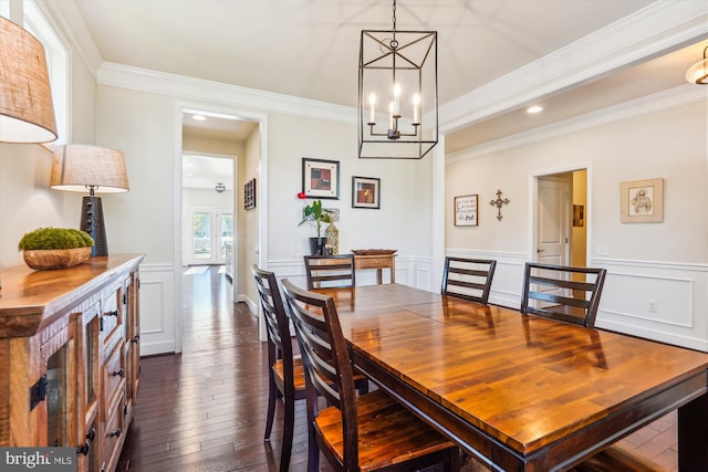 dining area with dark wood-type flooring, ornamental molding, and a notable chandelier