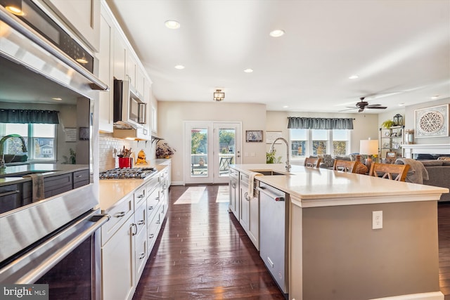 kitchen featuring a wealth of natural light, appliances with stainless steel finishes, a center island with sink, and white cabinets