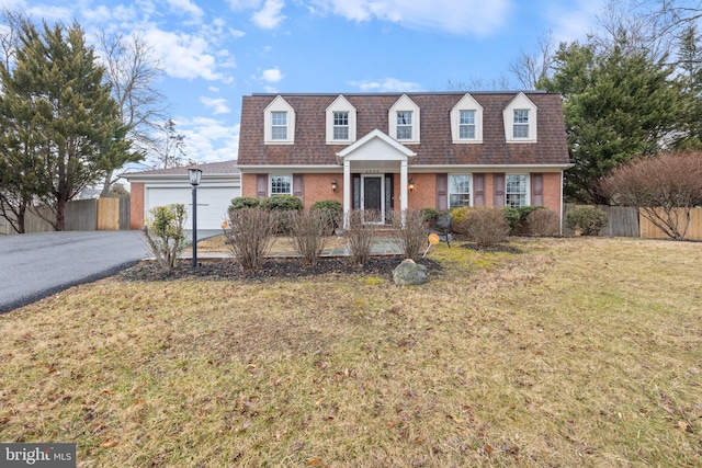 cape cod-style house with roof with shingles, fence, aphalt driveway, and brick siding