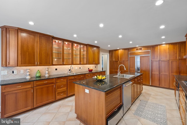 kitchen featuring brown cabinetry, paneled fridge, a sink, and stainless steel dishwasher