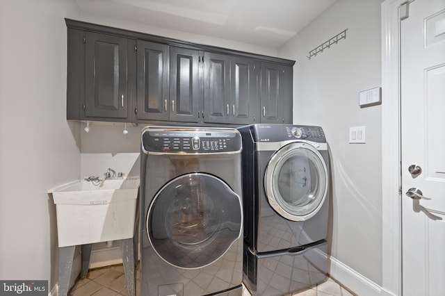 laundry area featuring light tile patterned floors, washing machine and clothes dryer, cabinet space, and baseboards