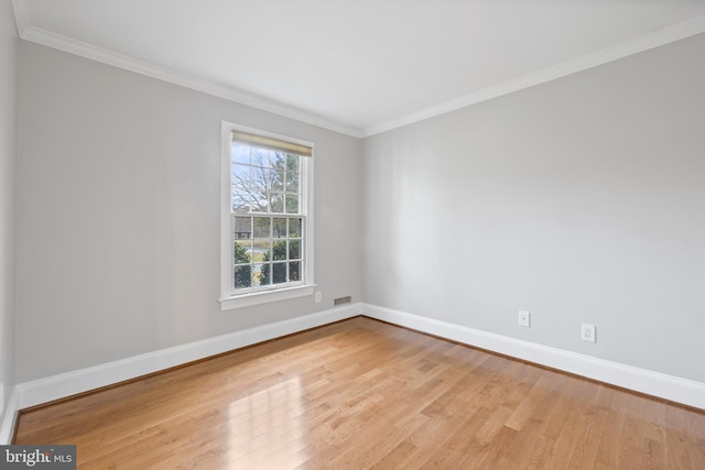 spare room featuring ornamental molding, visible vents, baseboards, and wood finished floors