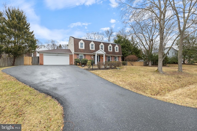 colonial inspired home with aphalt driveway, a front lawn, fence, and an attached garage