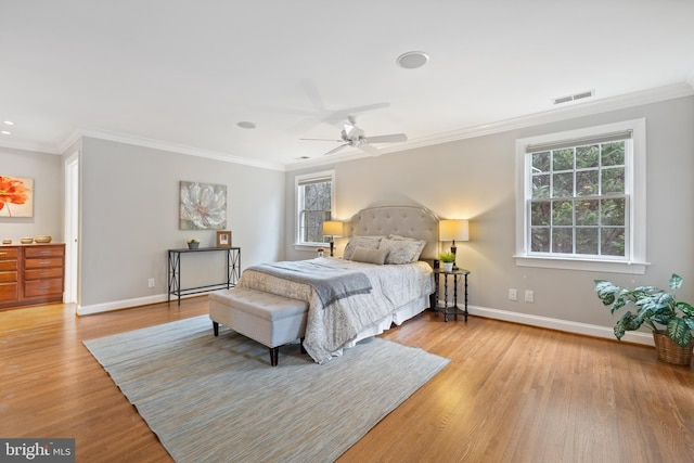 bedroom with ornamental molding, visible vents, baseboards, and wood finished floors