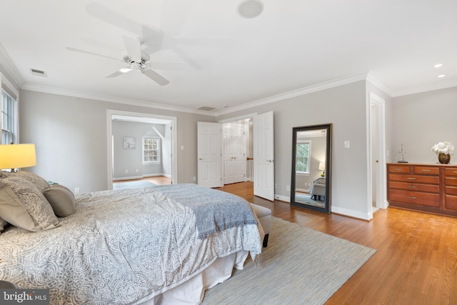 bedroom with crown molding, visible vents, baseboards, and wood finished floors