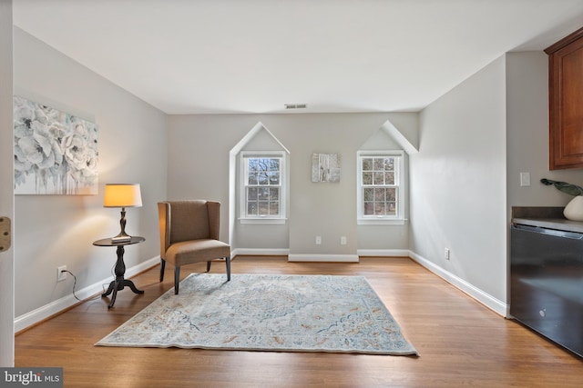 living area featuring light wood-style flooring, visible vents, and baseboards