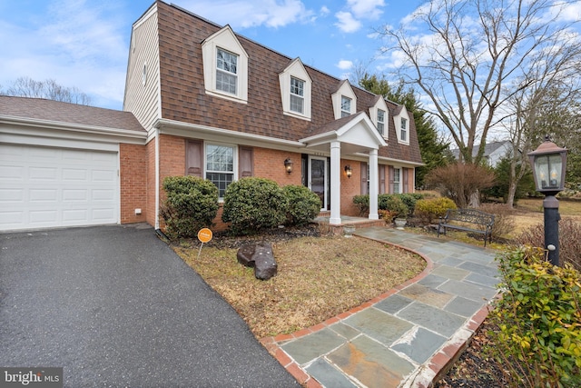 view of front of property with a shingled roof, brick siding, a garage, and aphalt driveway