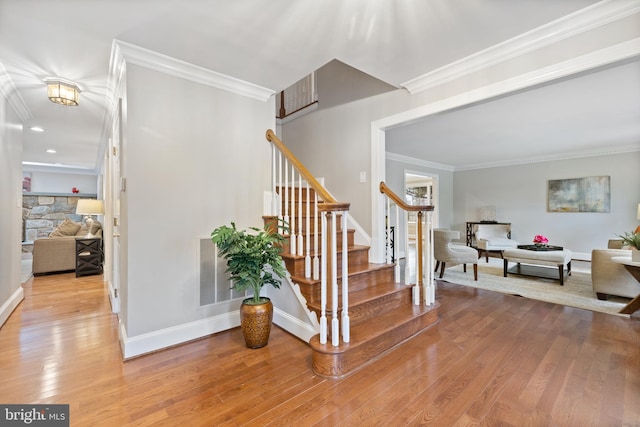 stairway with ornamental molding, wood finished floors, visible vents, and baseboards