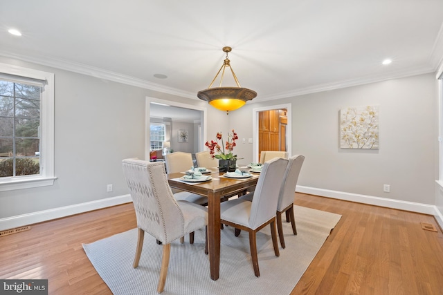 dining space with light wood-type flooring, visible vents, and crown molding