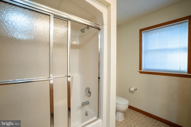 bathroom featuring bath / shower combo with glass door and toilet