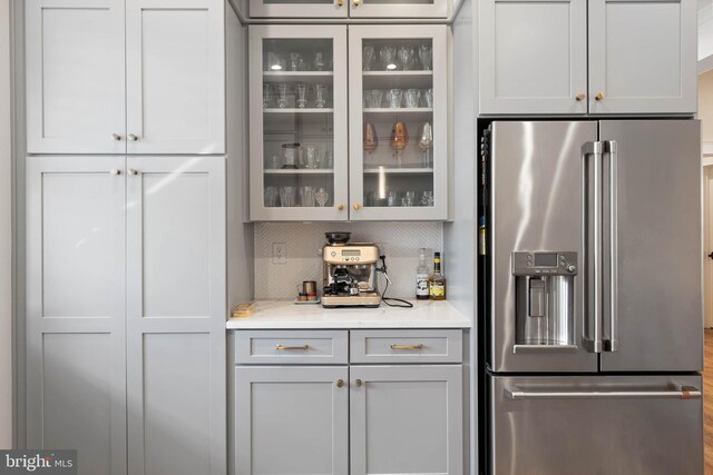 kitchen with high end fridge, light stone counters, gray cabinets, and tasteful backsplash