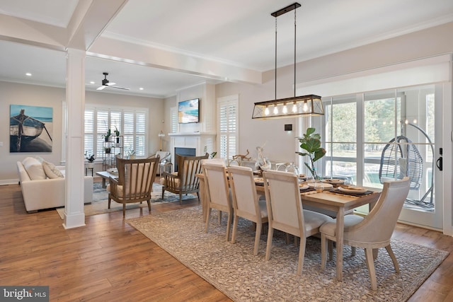 dining area featuring decorative columns, hardwood / wood-style flooring, ceiling fan, and ornamental molding