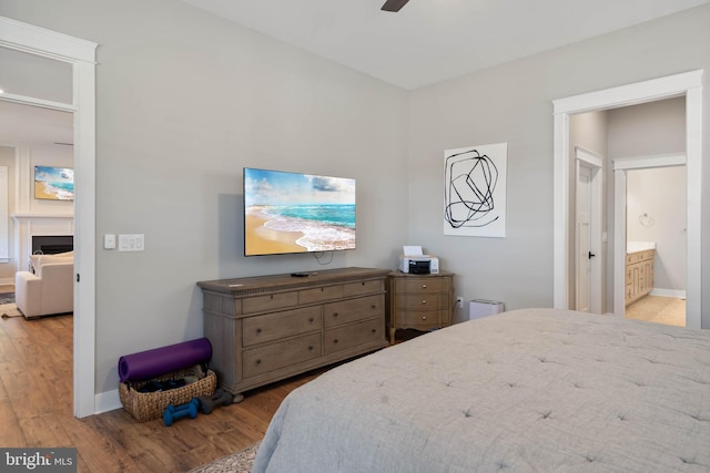 bedroom featuring ceiling fan, light hardwood / wood-style floors, and ensuite bath