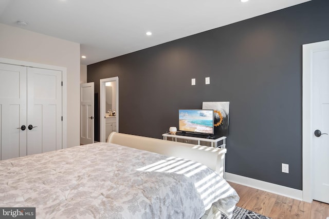 bedroom featuring light wood-type flooring, a closet, and connected bathroom