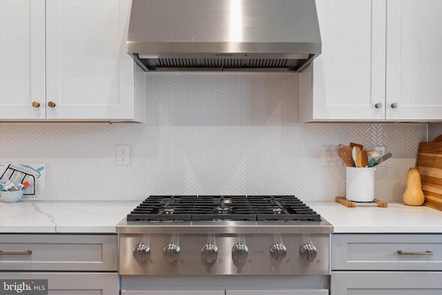 kitchen featuring light stone counters, backsplash, stainless steel gas cooktop, and wall chimney exhaust hood