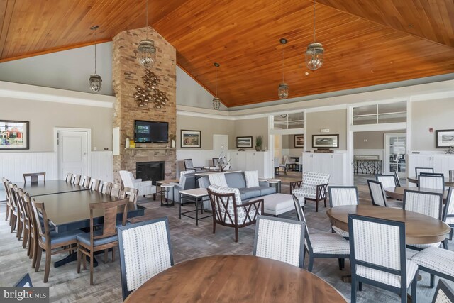 dining space featuring a stone fireplace, dark hardwood / wood-style flooring, high vaulted ceiling, and wooden ceiling