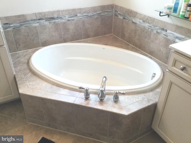 bathroom featuring vanity, a relaxing tiled tub, and tile patterned floors