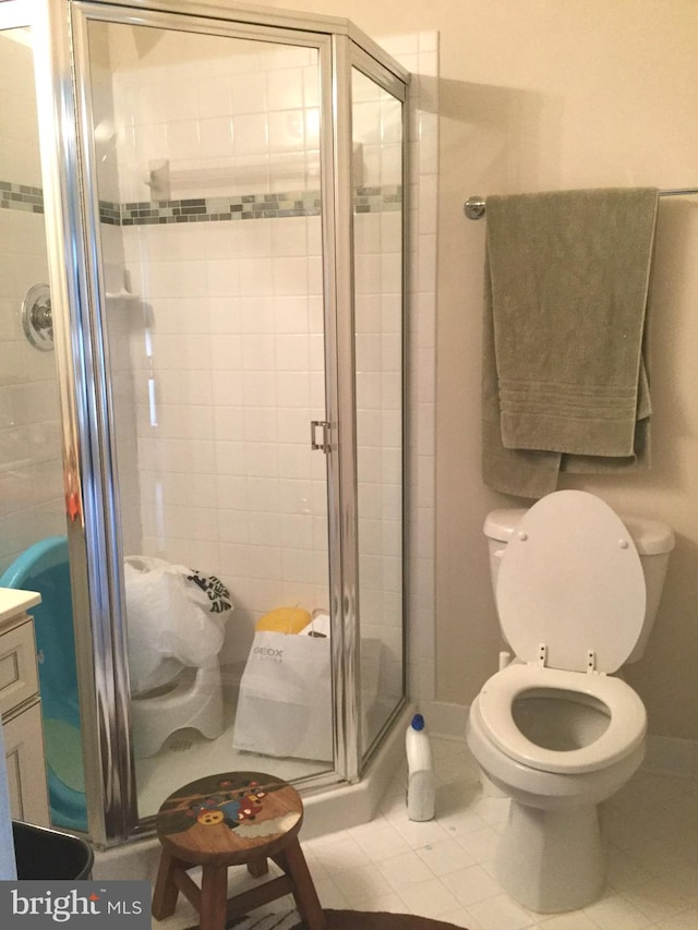 bathroom with vanity, walk in shower, toilet, and tile patterned flooring