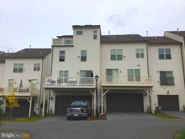 back of house with a balcony, central AC, a garage, and a carport