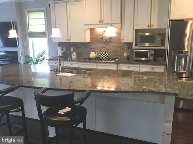 kitchen featuring sink, a kitchen breakfast bar, stainless steel appliances, white cabinets, and decorative backsplash