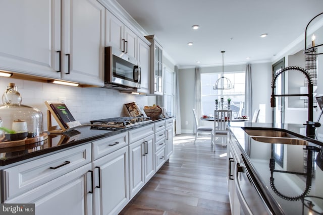 kitchen featuring ornamental molding, appliances with stainless steel finishes, light hardwood / wood-style flooring, and white cabinets