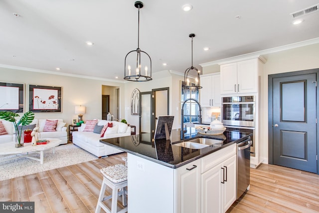 kitchen with sink, an island with sink, light hardwood / wood-style flooring, and white cabinetry