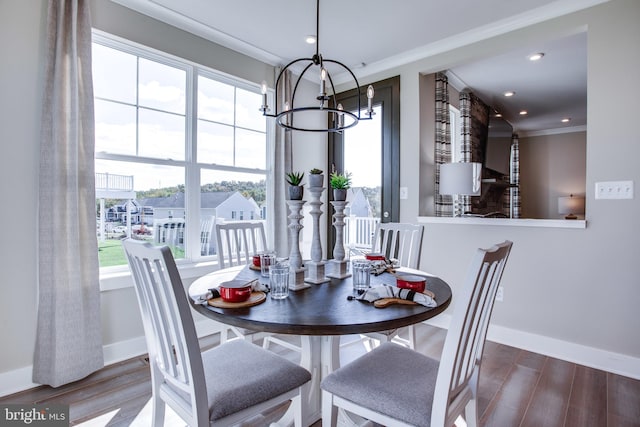 dining space featuring ornamental molding, hardwood / wood-style flooring, and an inviting chandelier