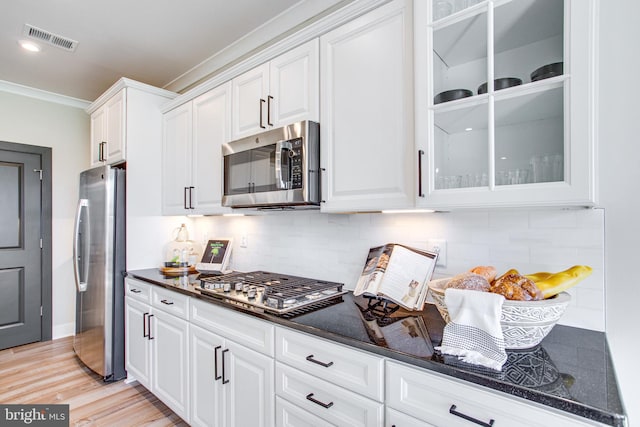 kitchen featuring decorative backsplash, white cabinets, light wood-type flooring, crown molding, and stainless steel appliances