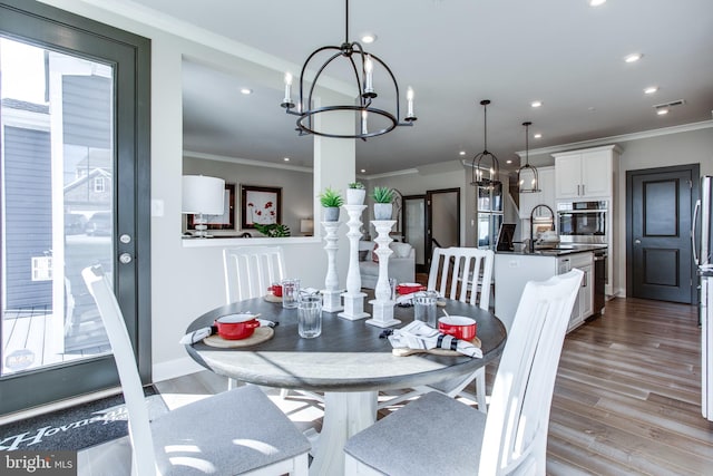 dining area with crown molding, sink, and light wood-type flooring