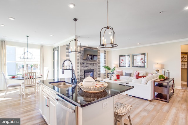 kitchen with sink, white cabinetry, pendant lighting, stainless steel dishwasher, and light hardwood / wood-style flooring