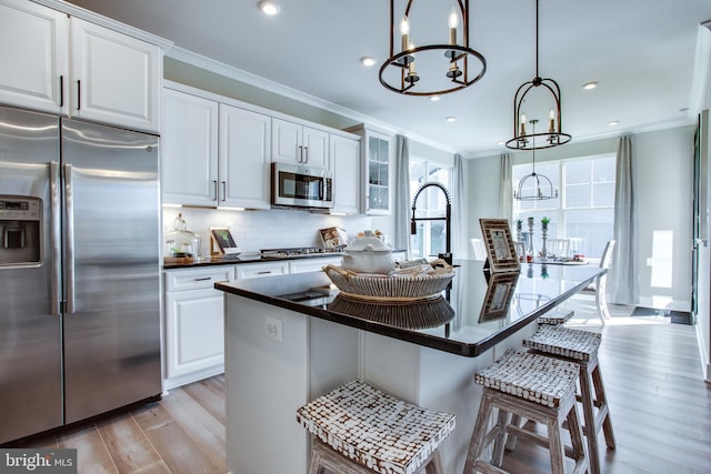 kitchen featuring appliances with stainless steel finishes, white cabinets, a kitchen bar, and light hardwood / wood-style floors