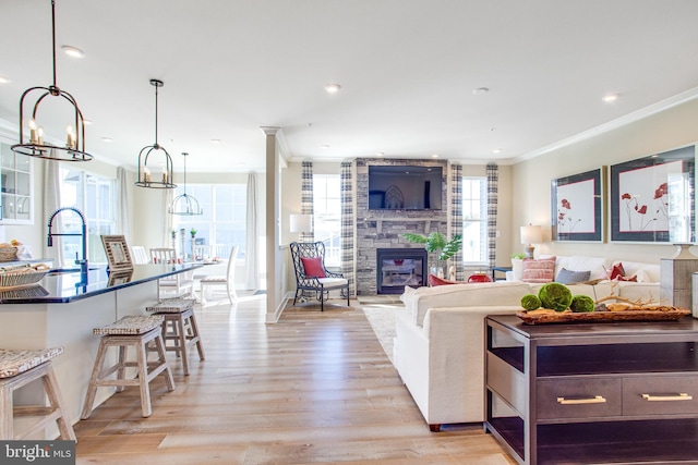 living room featuring light hardwood / wood-style flooring, a fireplace, plenty of natural light, and crown molding