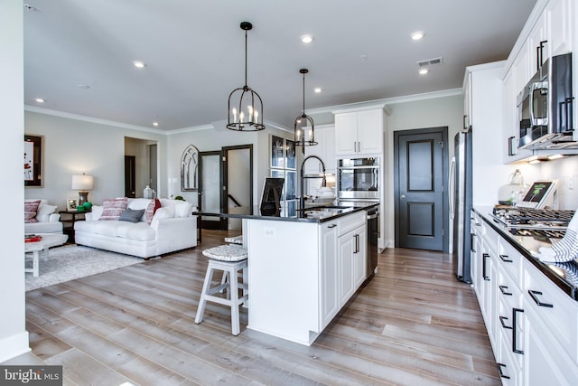 kitchen featuring light hardwood / wood-style flooring, stainless steel appliances, a center island with sink, sink, and white cabinets