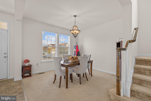 carpeted dining area featuring an inviting chandelier