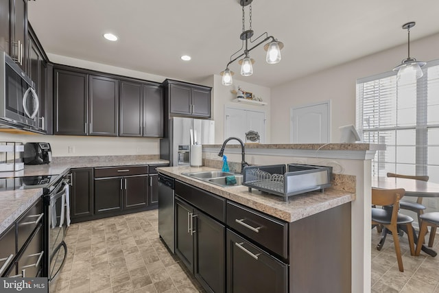 kitchen with stainless steel appliances, sink, pendant lighting, and a kitchen island with sink