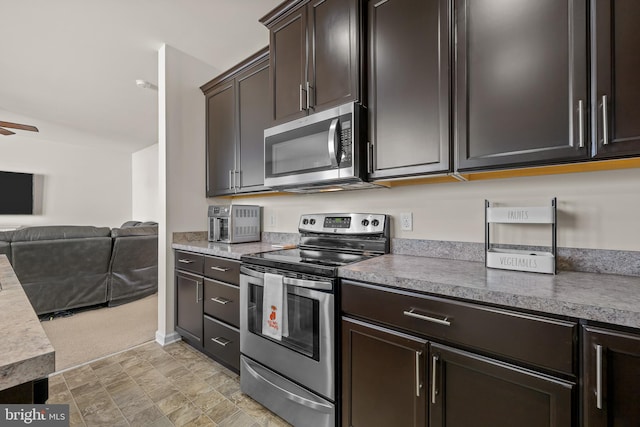 kitchen with ceiling fan, stainless steel appliances, dark brown cabinetry, and light colored carpet