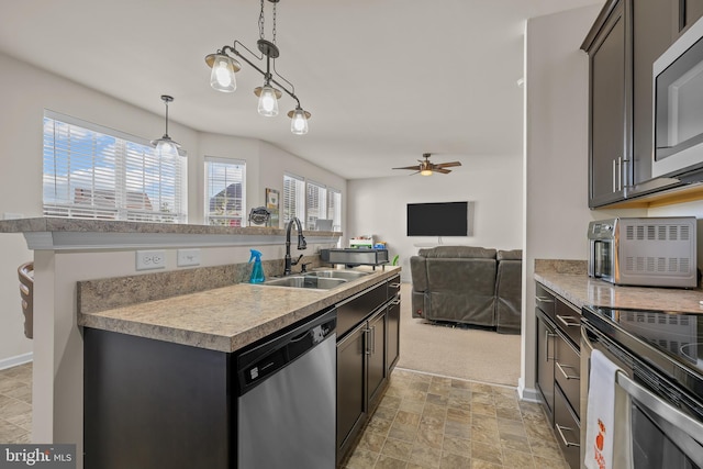 kitchen with hanging light fixtures, stainless steel appliances, sink, and a wealth of natural light