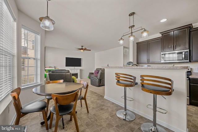 dining space featuring a tiled fireplace, a healthy amount of sunlight, and ceiling fan