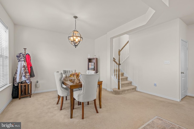 carpeted dining area with a chandelier