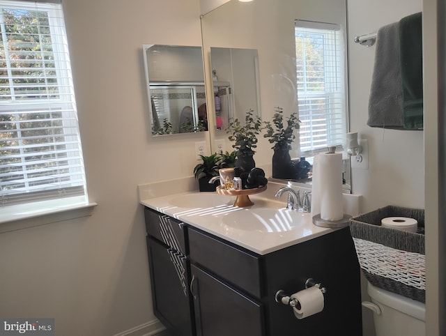 bathroom featuring toilet, walk in shower, and vanity