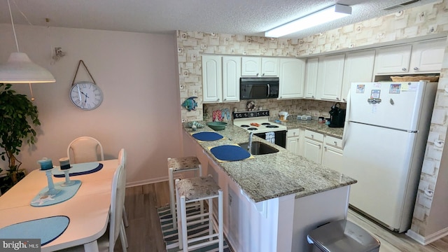 kitchen with white appliances, a kitchen breakfast bar, and white cabinets