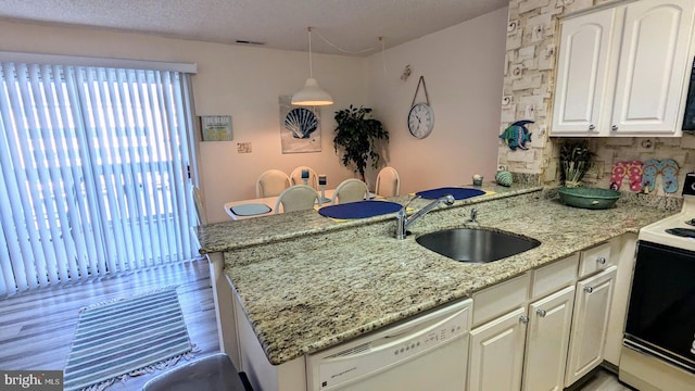 kitchen with kitchen peninsula, sink, decorative light fixtures, light wood-type flooring, and white appliances