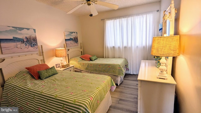 bedroom featuring ceiling fan, wood-type flooring, and a textured ceiling