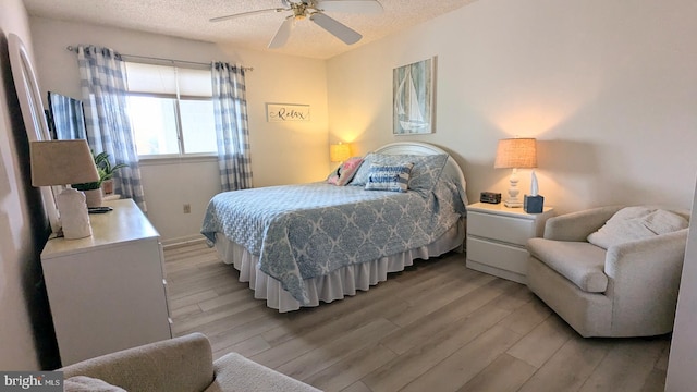 bedroom featuring ceiling fan, a textured ceiling, and light wood-type flooring