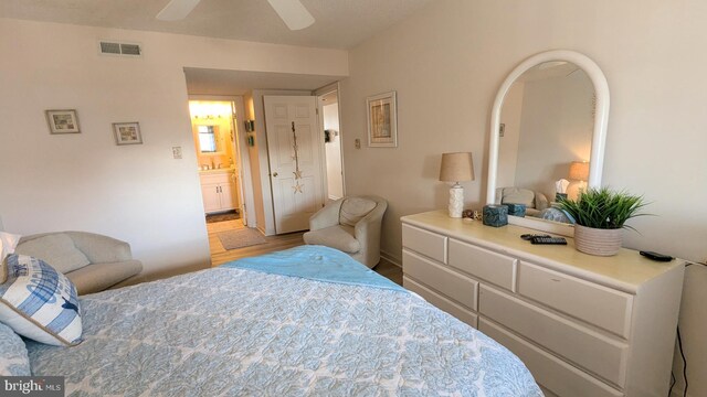 bedroom featuring light hardwood / wood-style flooring, ensuite bathroom, and ceiling fan